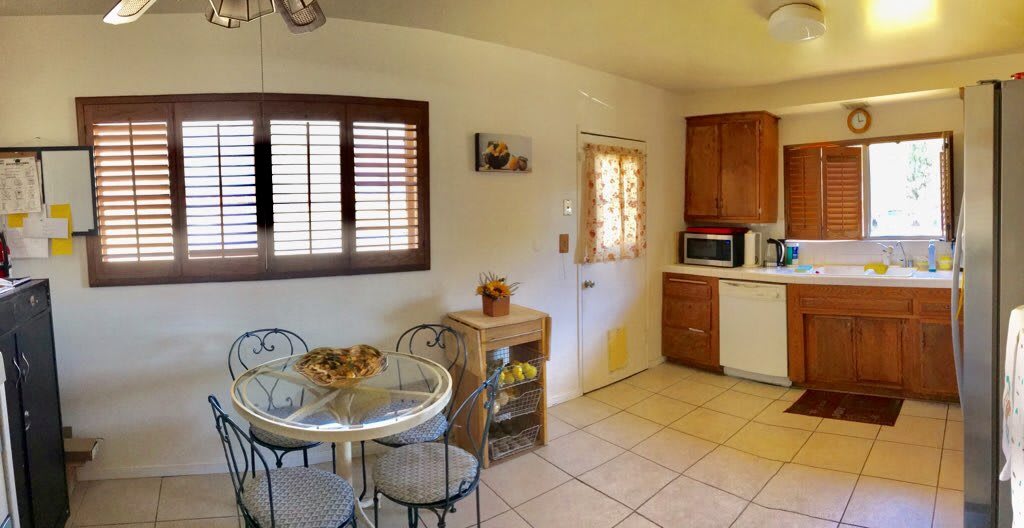 A cozy kitchen with a small dining area featuring a round table and chairs, framed by wooden cabinets and natural light.