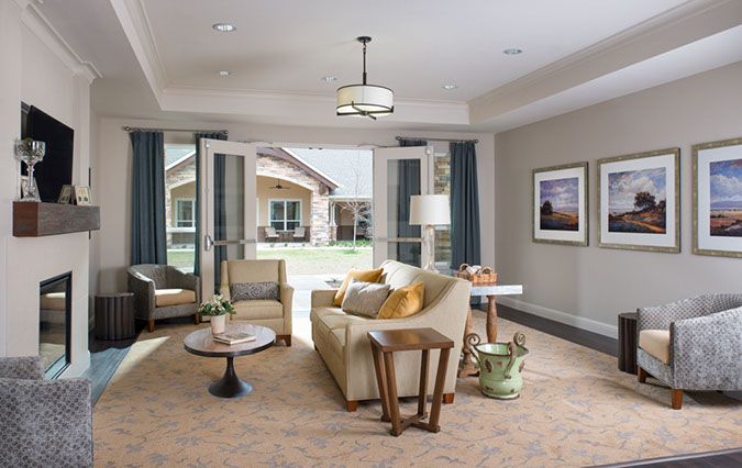 A modern, cozy living room with neutral colors and natural light coming through open doors.