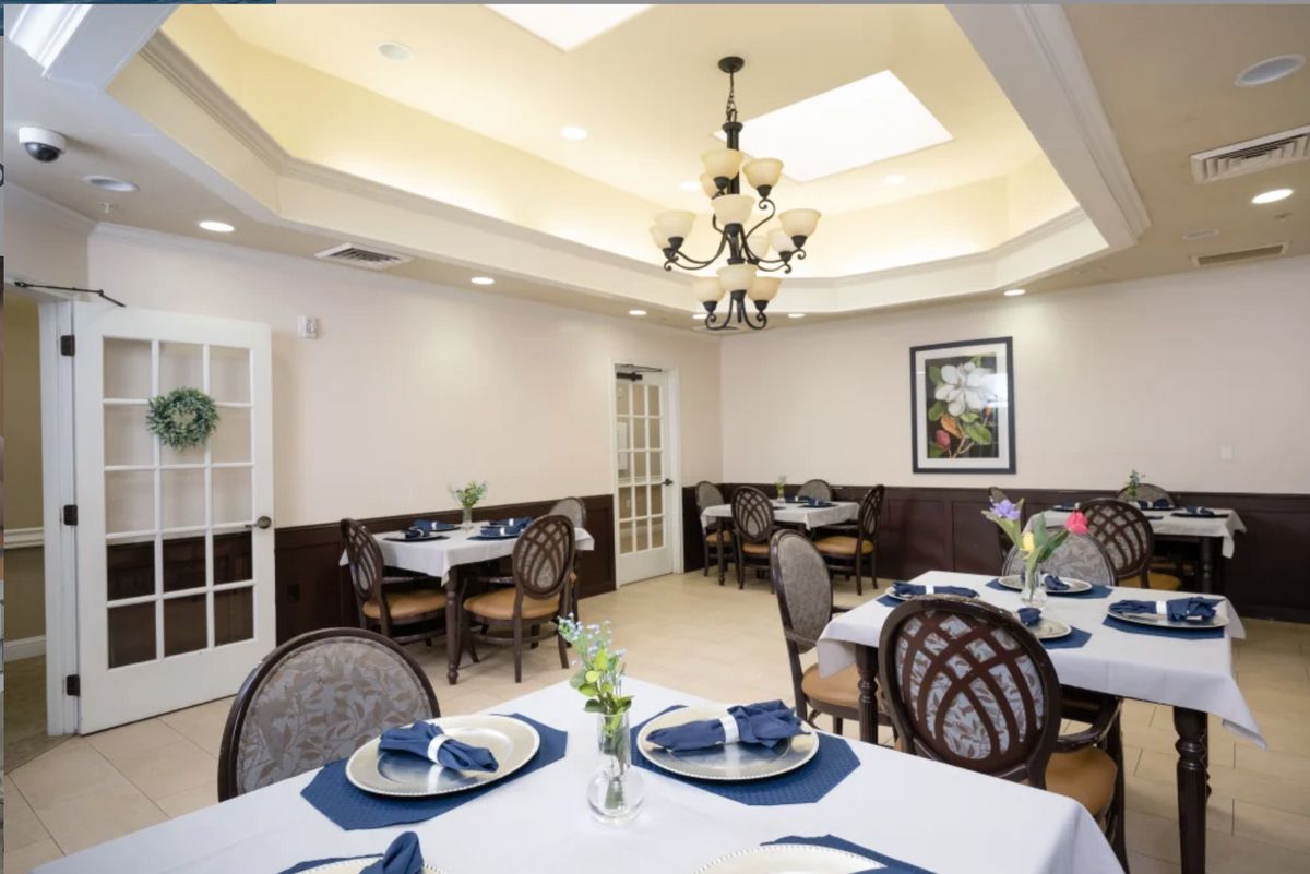 An elegant dining room with neatly arranged tables and a chandelier.