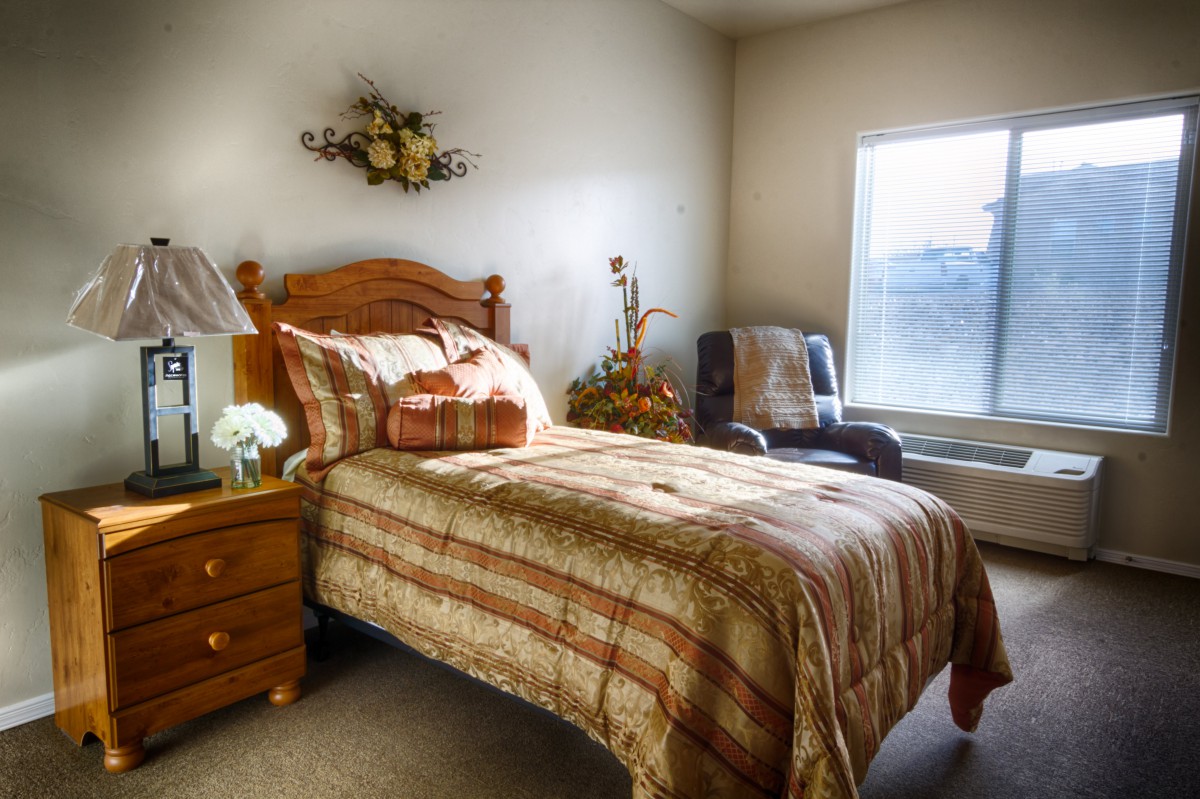 A cozy bedroom with a single bed, decorated with warm tones and natural light streaming through the window.