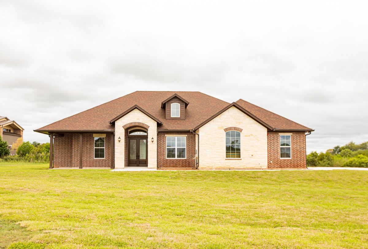A modern brick suburban house with a large front lawn.