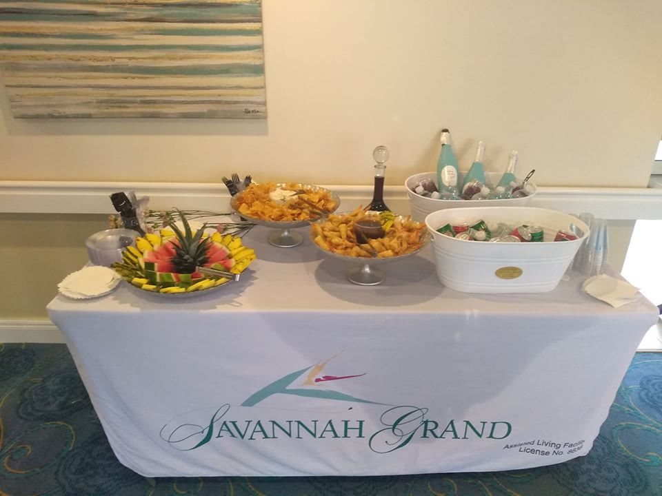 A buffet table set up at Savannah Grand, featuring a selection of fruits, snacks, and beverages.
