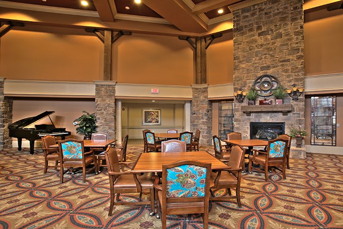 A cozy dining area with wooden tables and chairs, a fireplace, and warm decor.