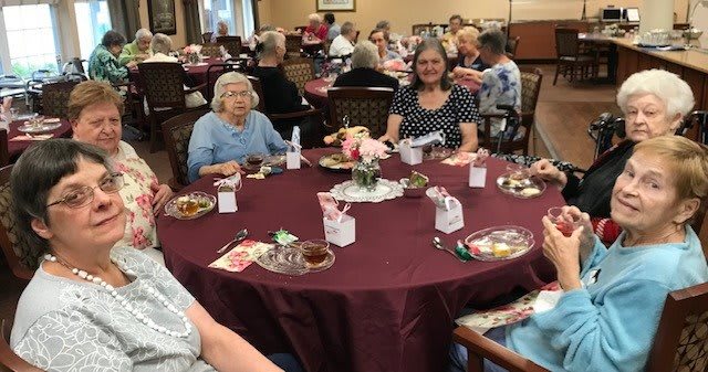 A group of elderly individuals enjoying a social gathering at a dining table.