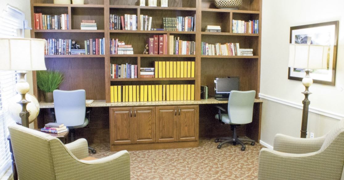 A cozy library area with bookshelves and two computer workstations.