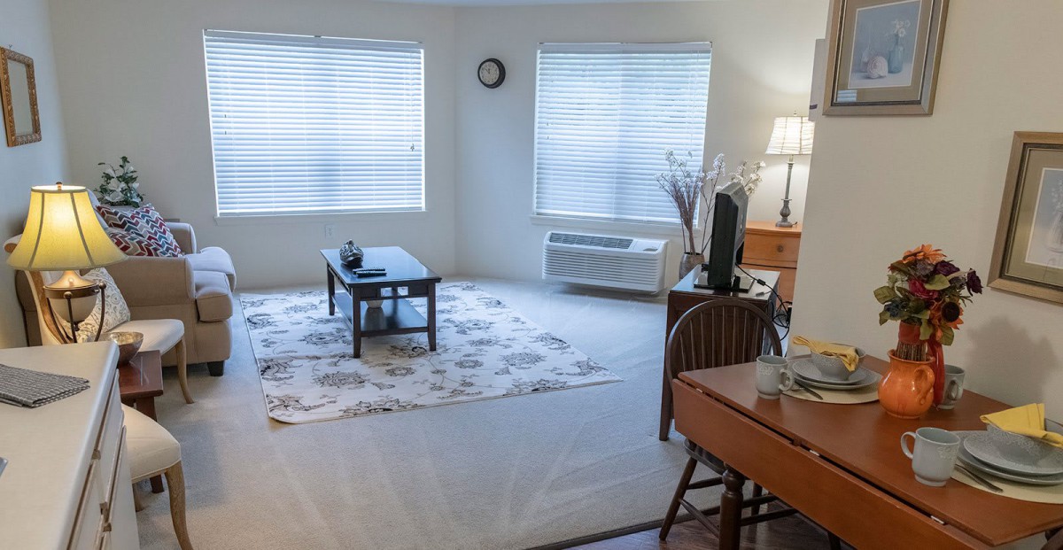 A cozy living room with a coffee table, patterned carpet, and soft lighting.