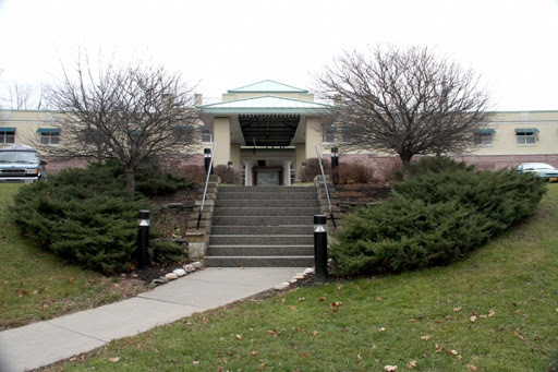 A welcoming entrance to a building surrounded by neatly landscaped greenery and steps.