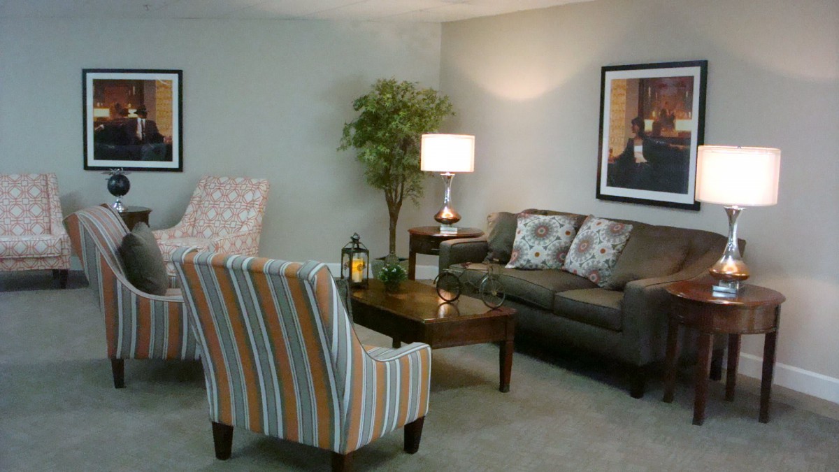 A cozy living room with a sofa, armchair, and a coffee table, complemented by a lamp and decorative elements.