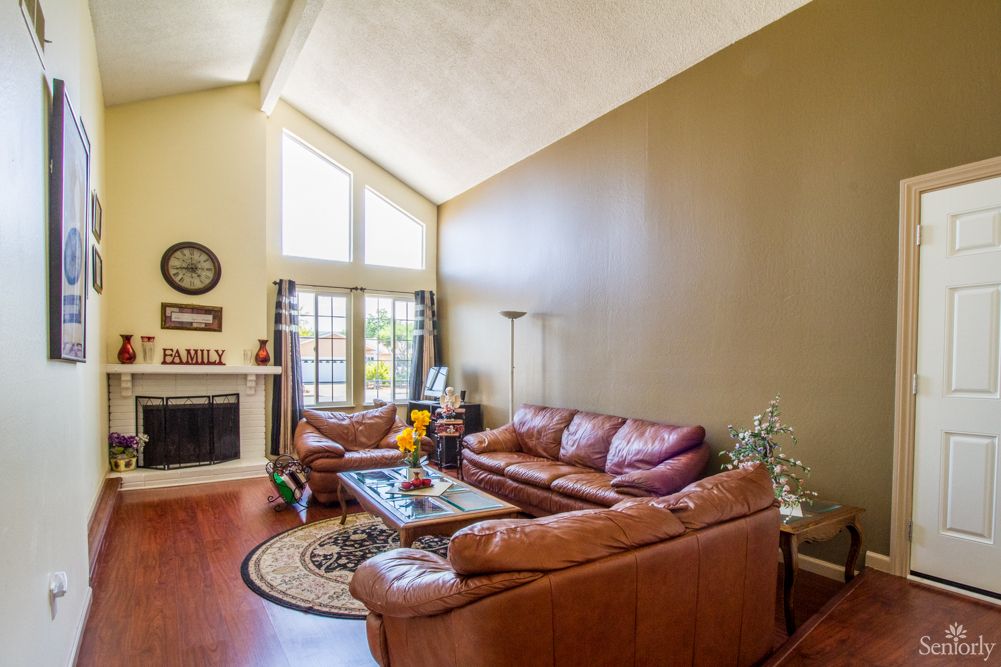 A cozy living room featuring leather sofas, a fireplace, and a vaulted ceiling.