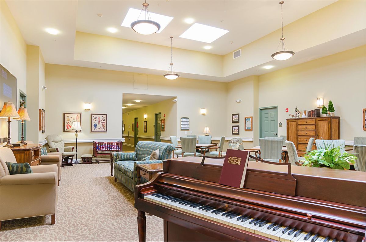 A spacious living room with a piano and comfortable seating arrangements.