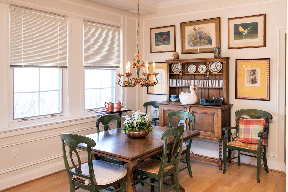 A traditional dining room with wooden furniture, decorative plates, and a classic chandelier.