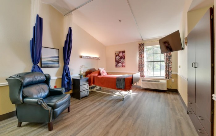 A well-lit hospital room with a bed, a comfortable chair, and decorative elements.