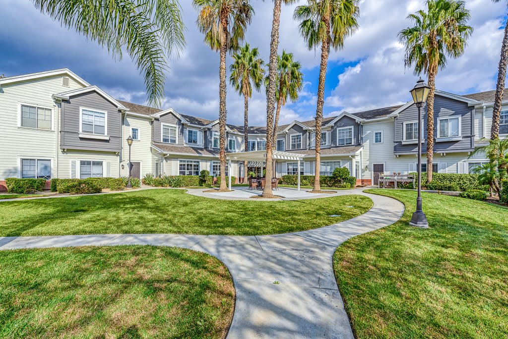 A beautiful residential building surrounded by palm trees and a well-maintained lawn with a winding pathway.