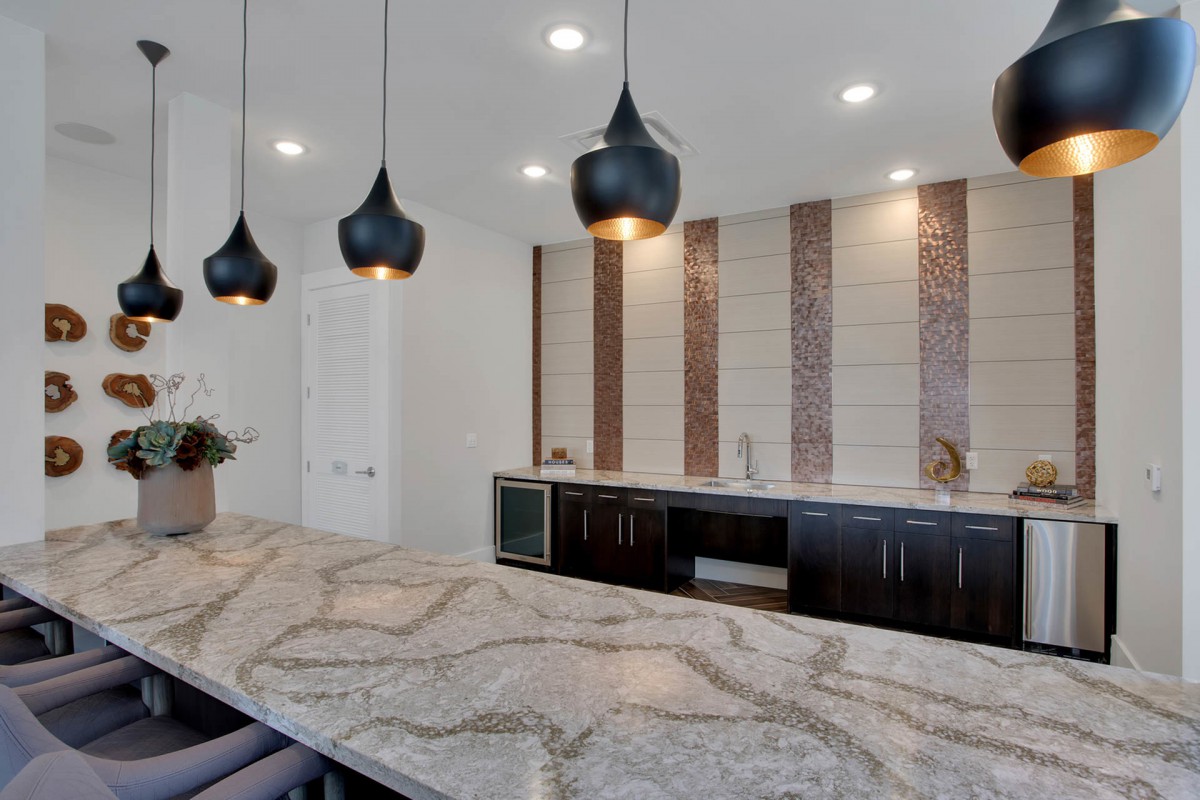 A modern kitchen with a marble countertop and stylish pendant lighting.