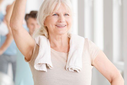 Elderly woman smiling during a fitness class.