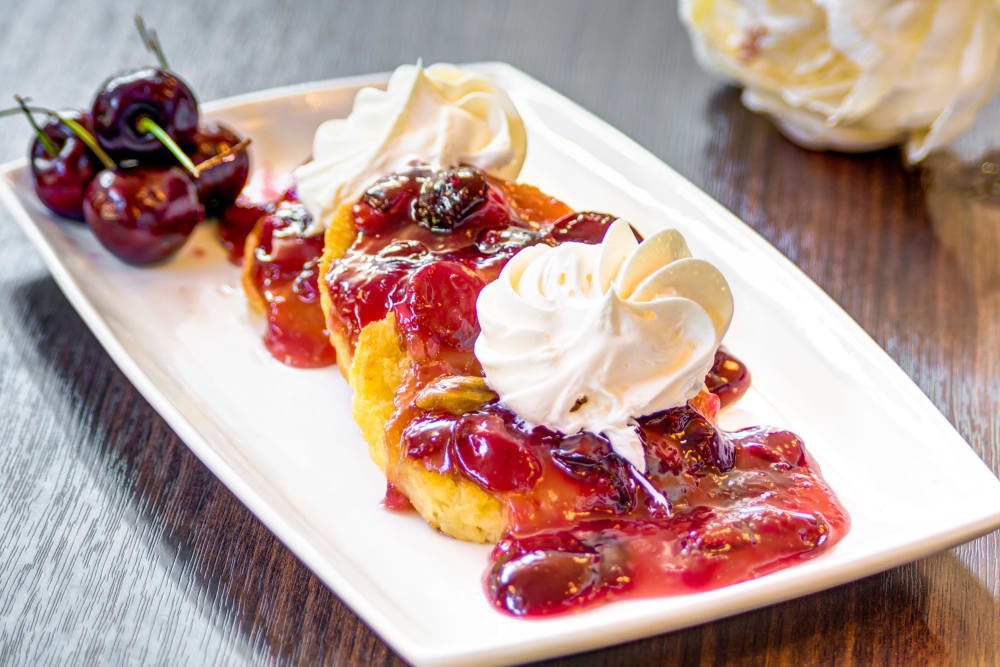 A delicious dessert topped with cherry sauce and whipped cream.