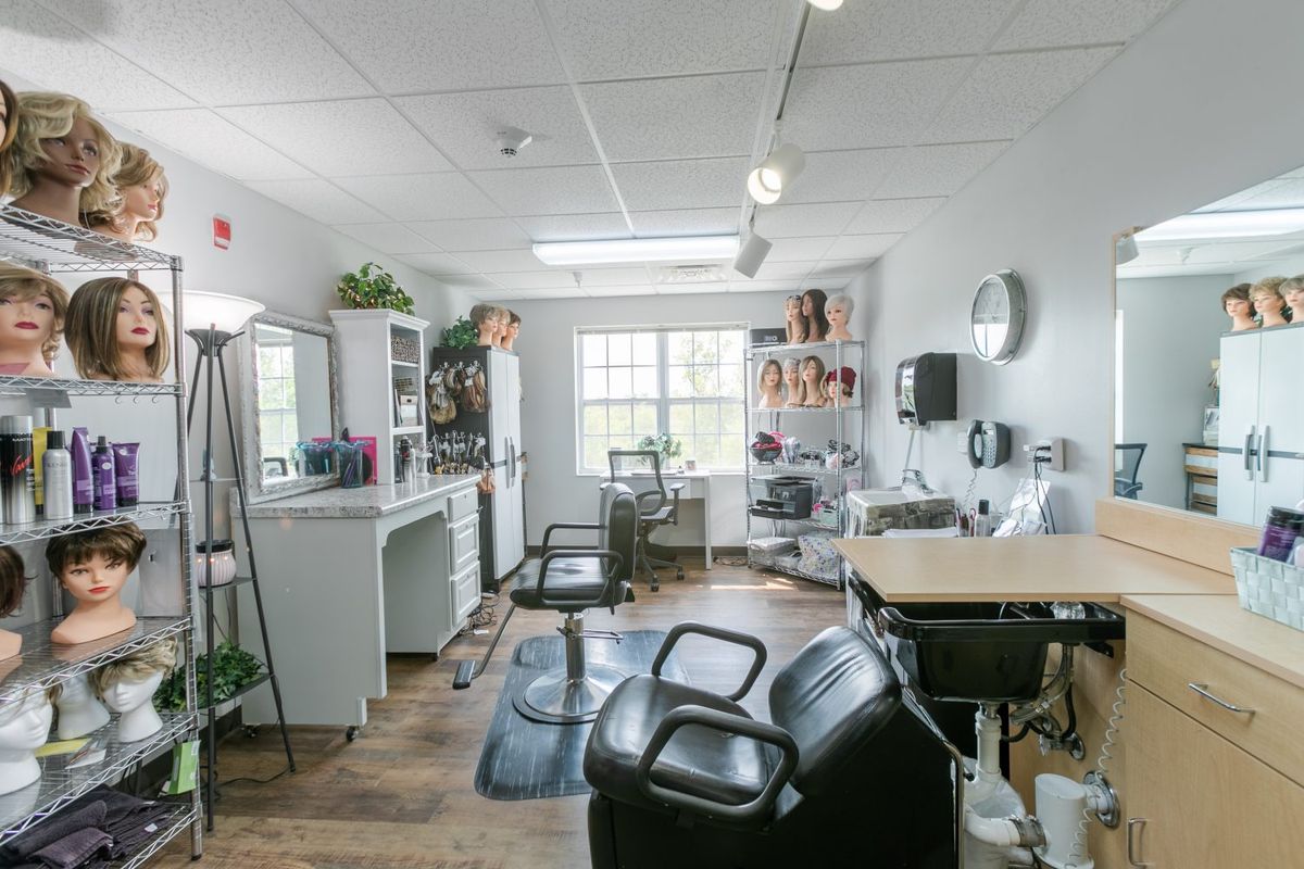A well-lit hair salon equipped with chairs, mirrors, and various styling tools.