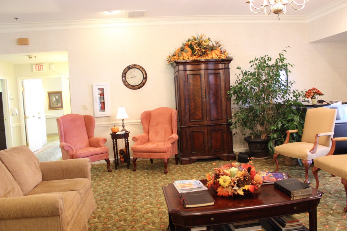 A cozy living room with armchairs, a coffee table decorated with autumn-themed ornaments, and a large cabinet.