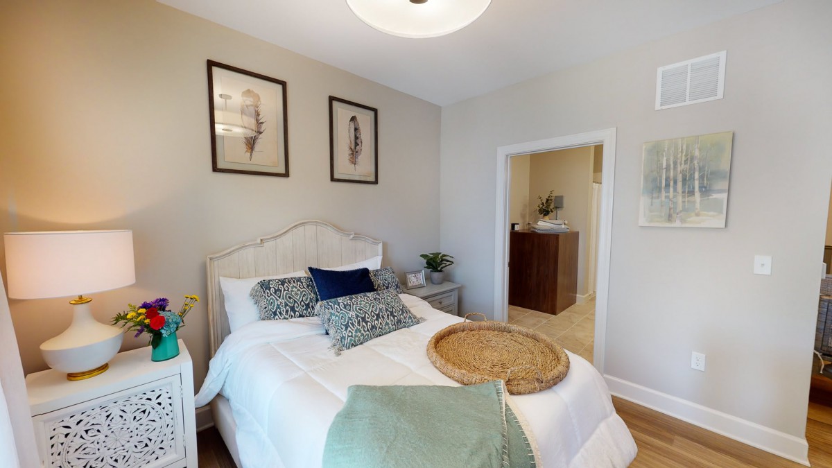 A cozy and modern bedroom featuring a neatly made bed with decorative pillows, wall art, and a minimalist design.