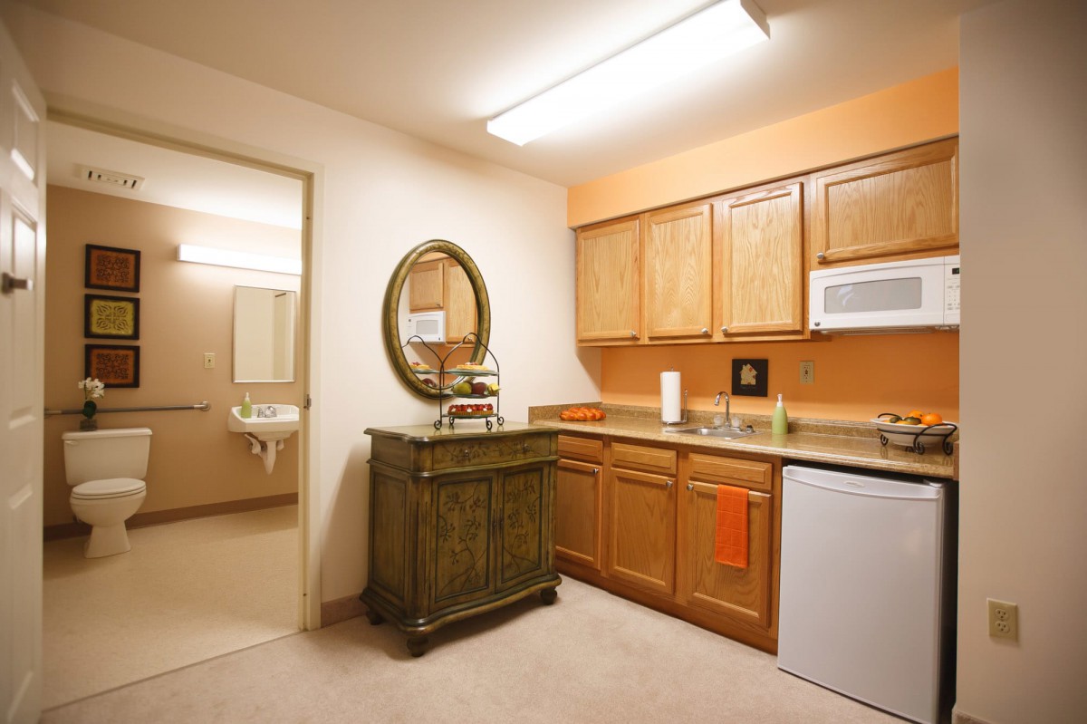 A small kitchenette with wooden cabinets, a microwave, and a mini fridge.