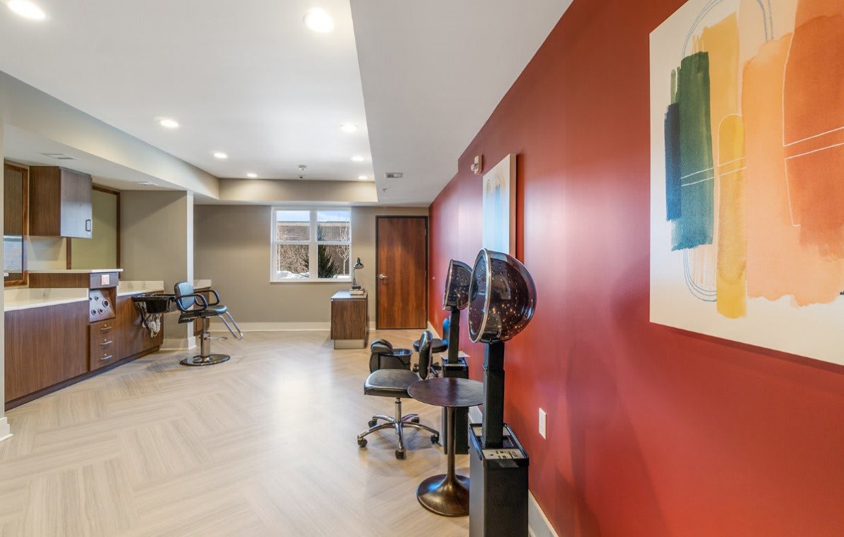 A modern salon interior with styling chairs, mirrors, and bright lighting against a red accent wall.