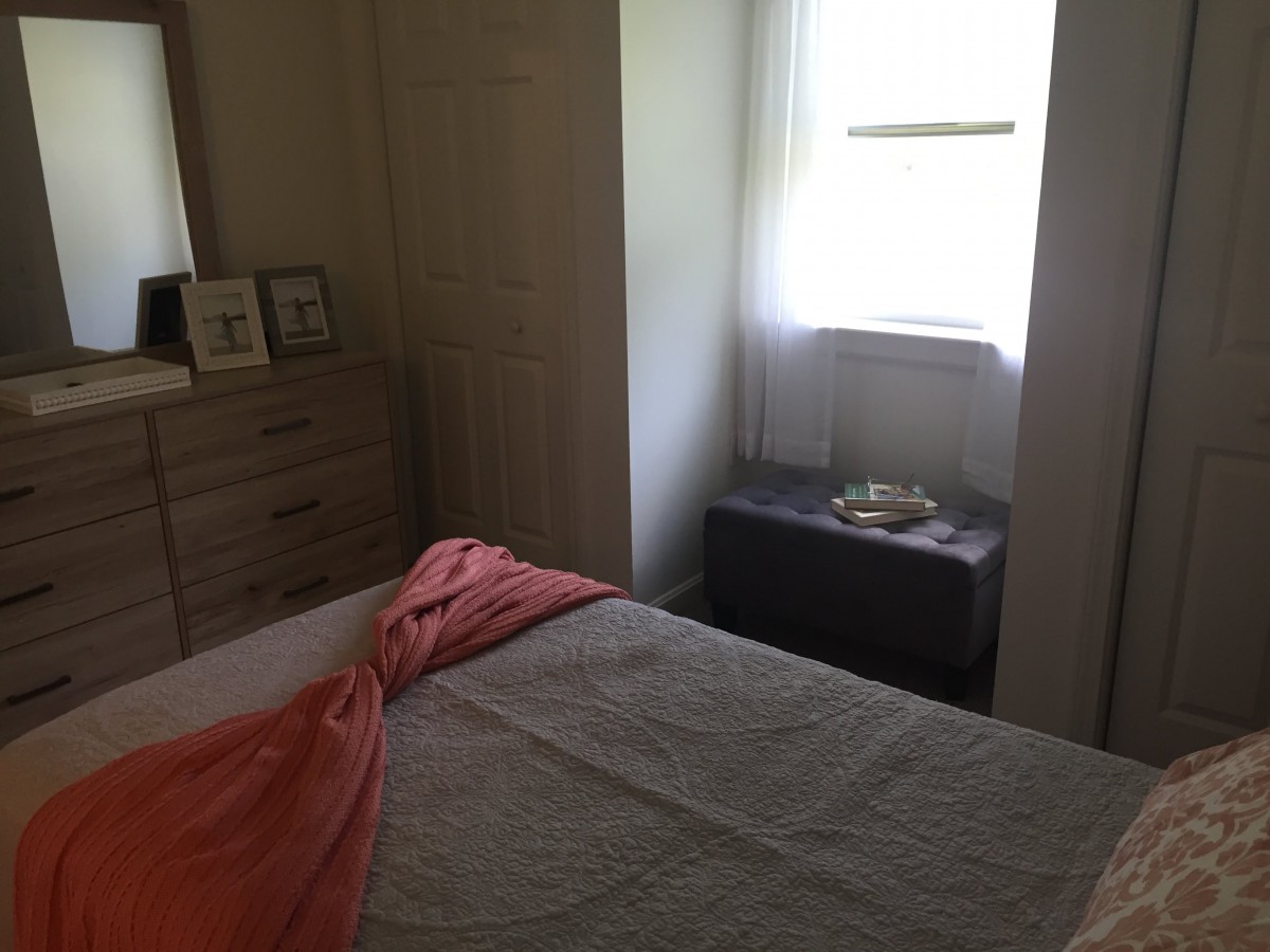 A cozy bedroom with a bed, dresser, and window letting in natural light.