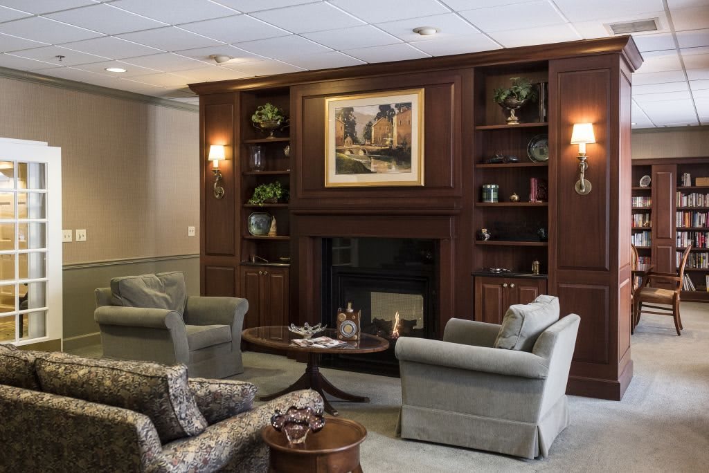 A cozy lounge area featuring a fireplace, armchairs, and bookshelves.