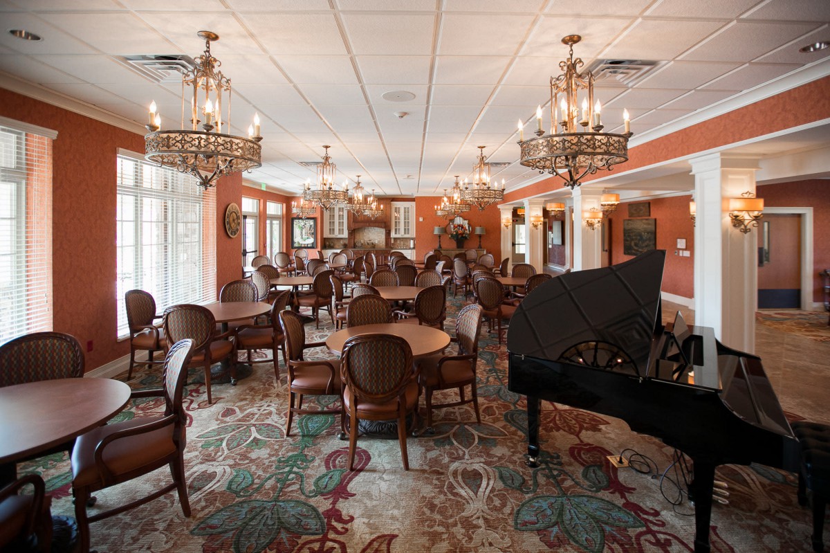 An elegant restaurant dining area featuring chandeliers, a grand piano, and classic decor.