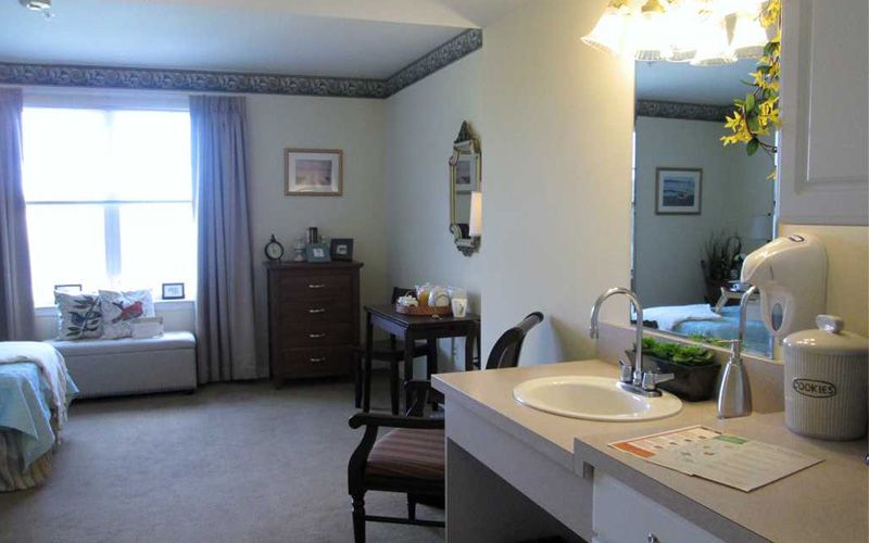 A cozy bedroom with a dressing area, featuring a sink and mirror.
