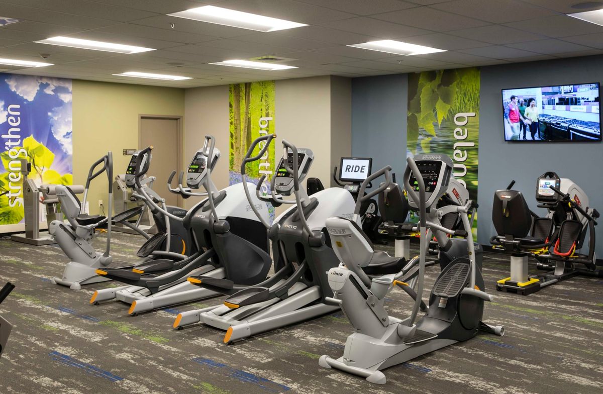 A row of elliptical machines in a modern gym setting.