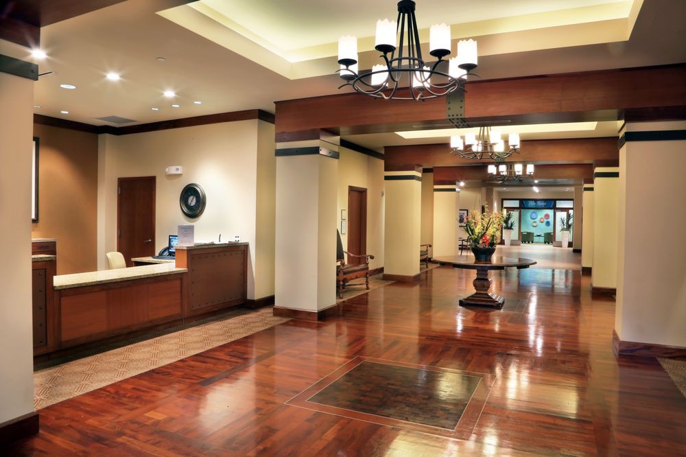 A spacious hotel lobby featuring elegant chandeliers and polished wooden floors.