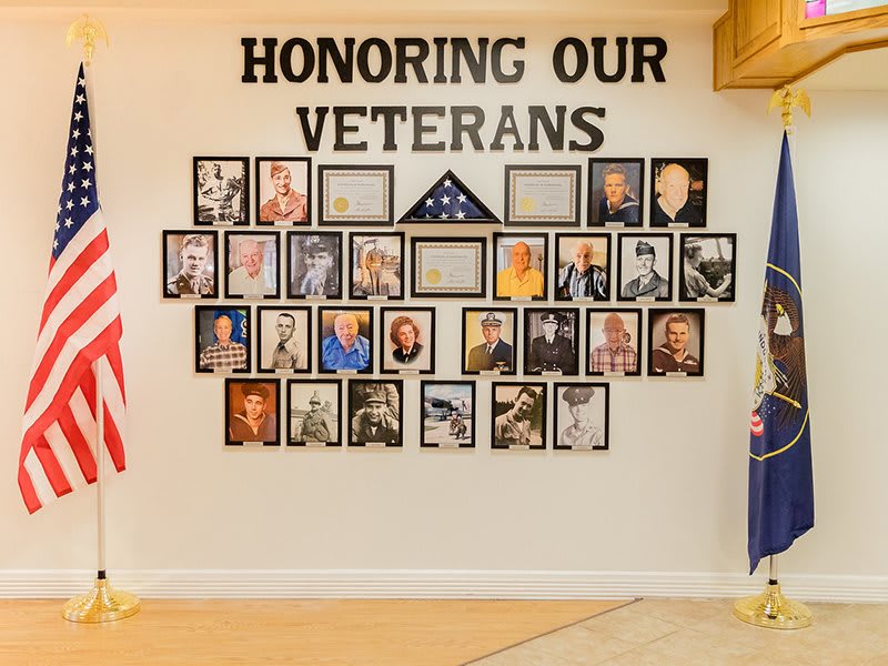 A wall dedicated to honoring veterans, featuring photographs and an American flag.