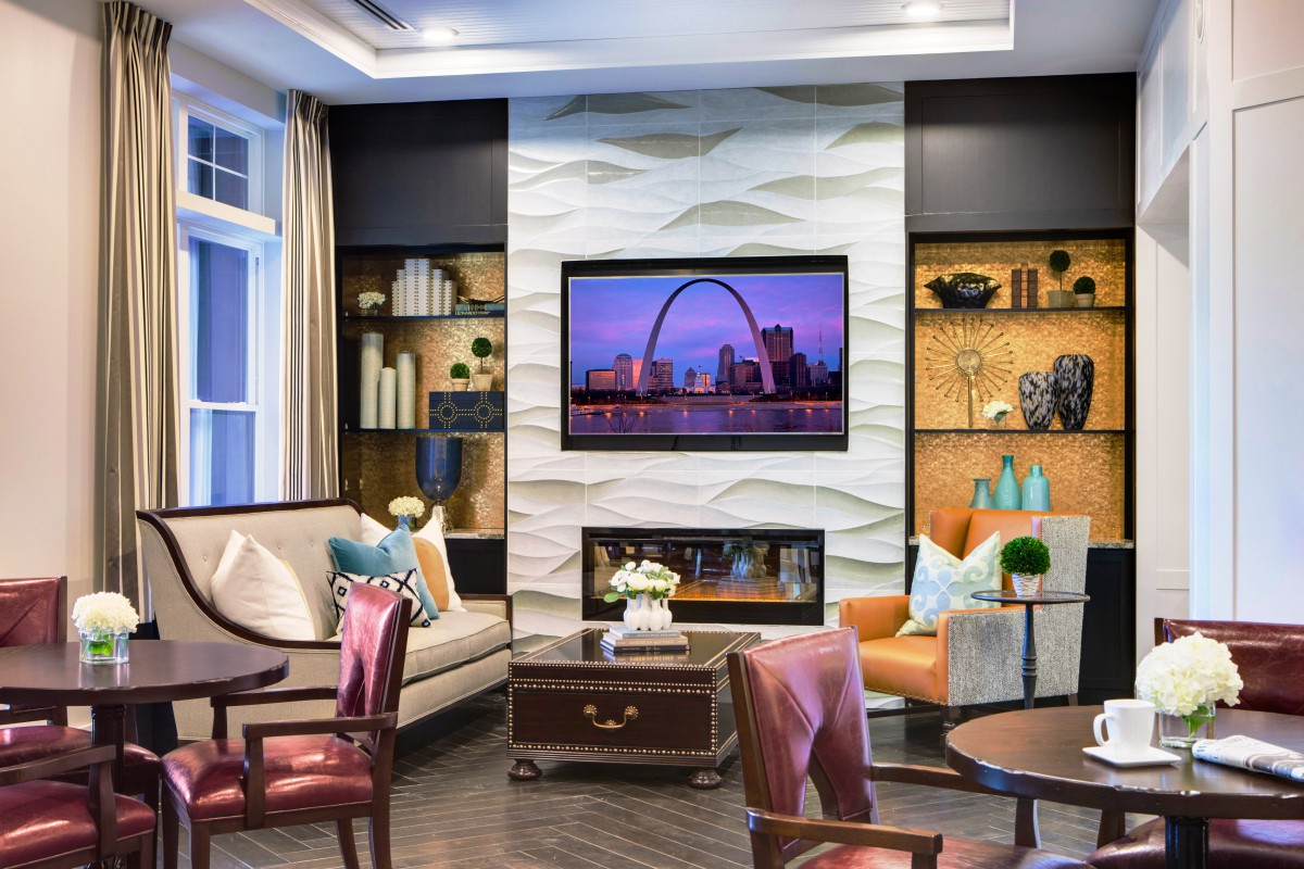A stylish living room with elegant furniture and a television mounted above a decorative fireplace.