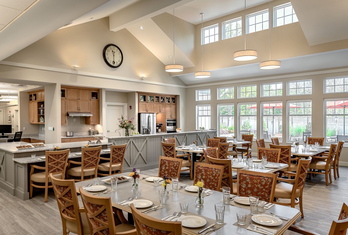 A bright and spacious dining room with set tables and a view of the kitchen area.