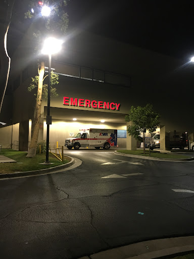 Emergency entrance of a hospital at night with an ambulance parked outside.