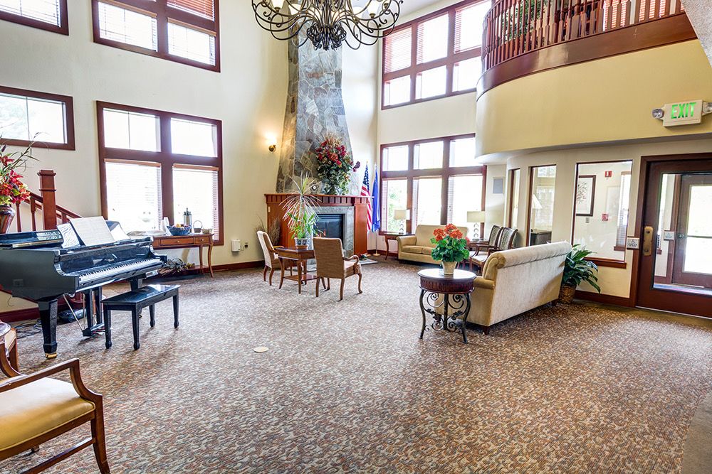 A spacious and elegantly designed living room with high ceilings, large windows, a central fireplace, and comfortable seating.