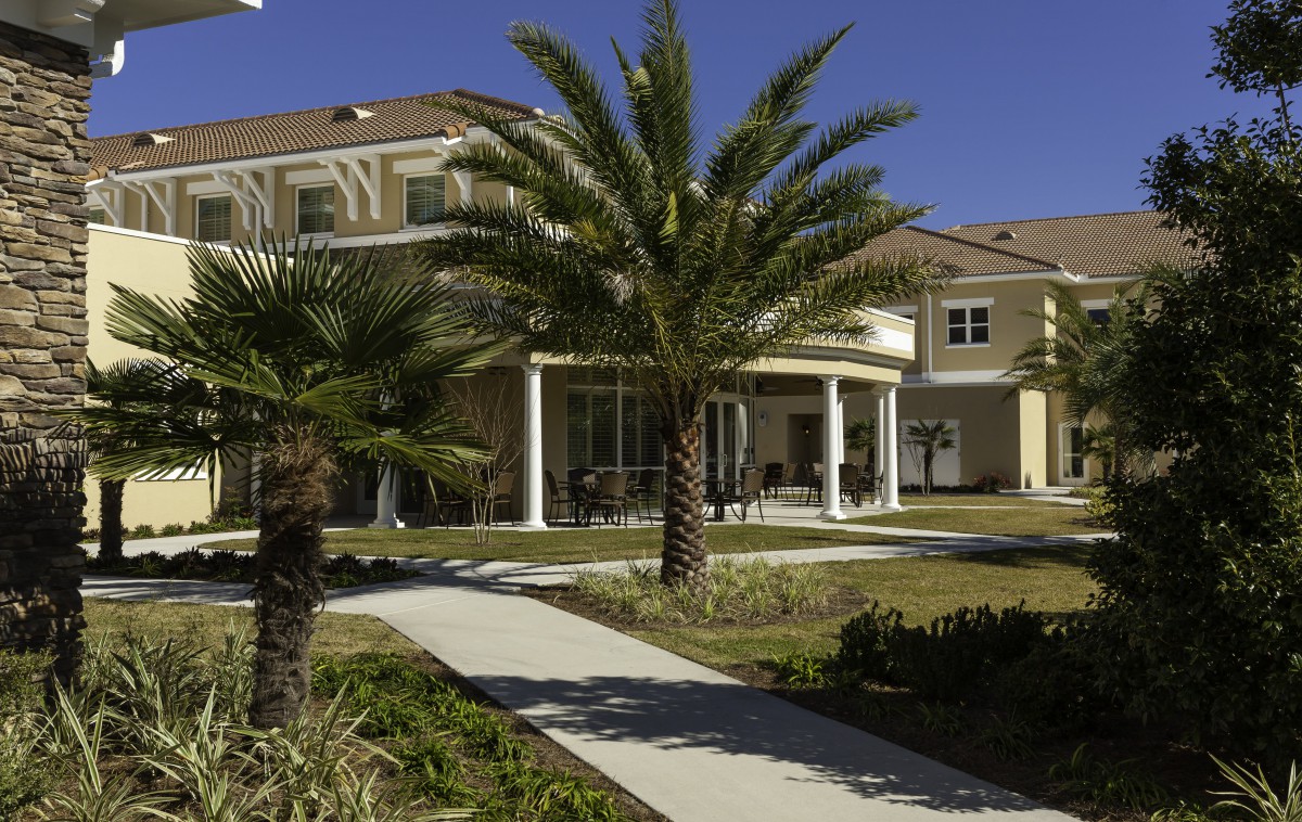 A suburban house with a front lawn and palm trees on a sunny day.