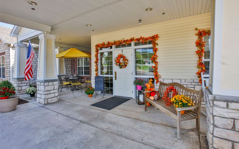 An inviting entrance decorated with autumn-themed accessories, including a wreath and seasonal plants.