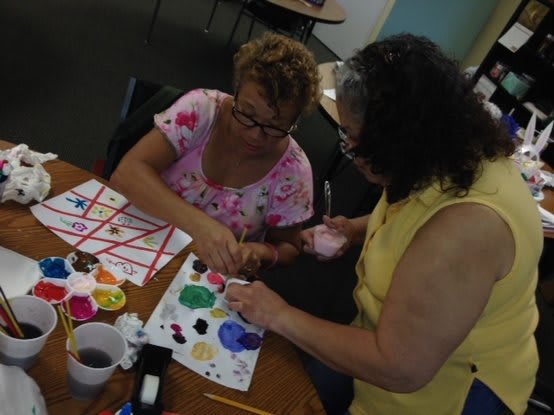 Two women engaging in a painting activity indoors.