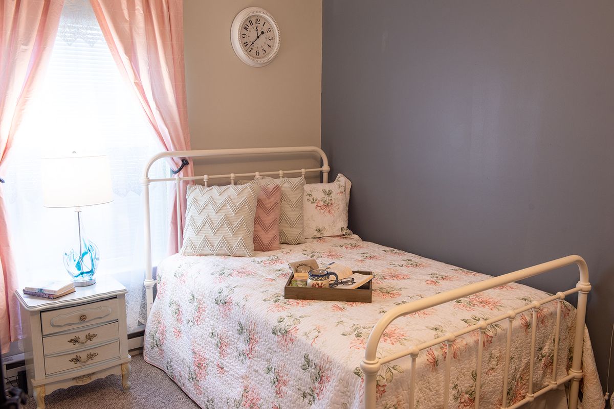 A cozy bedroom with floral bedding and a simple, elegant decor.