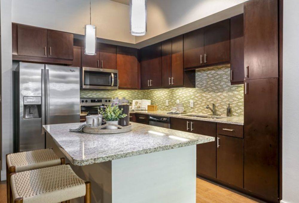 A modern kitchen featuring dark wood cabinets, granite countertops, and stainless steel appliances.