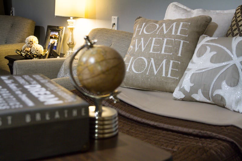 A cozy living room setting featuring a decorative globe and a pillow with 'Home Sweet Home' text.