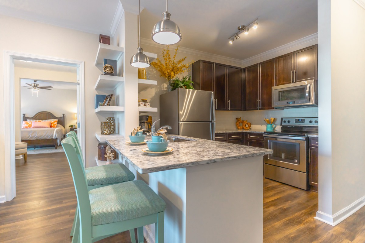 A modern kitchen with stylish countertops, stainless steel appliances, and decorative open shelves.