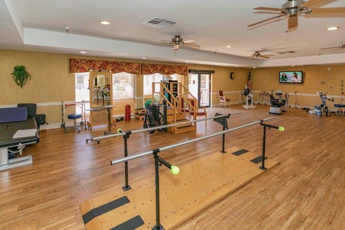 A well-equipped rehabilitation room featuring parallel bars and various exercise equipment for physical therapy.