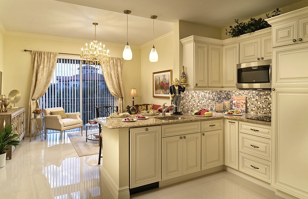 A stylish and modern kitchen with cream-colored cabinets, a decorative backsplash, and elegant lighting fixtures.