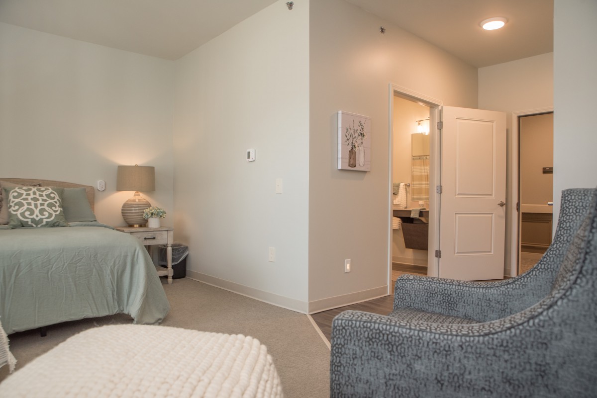 A cozy bedroom with a bed, nightstand, and an open door leading to another room.