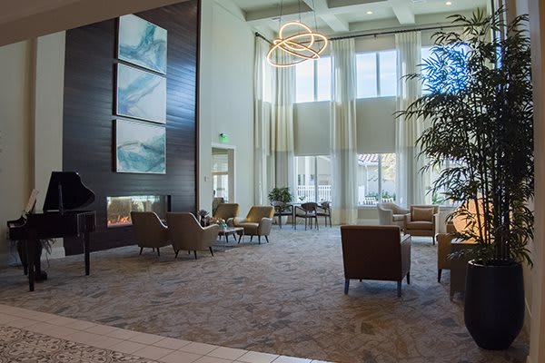 A spacious and modern lobby with ample seating, large windows, and a decorative chandelier.