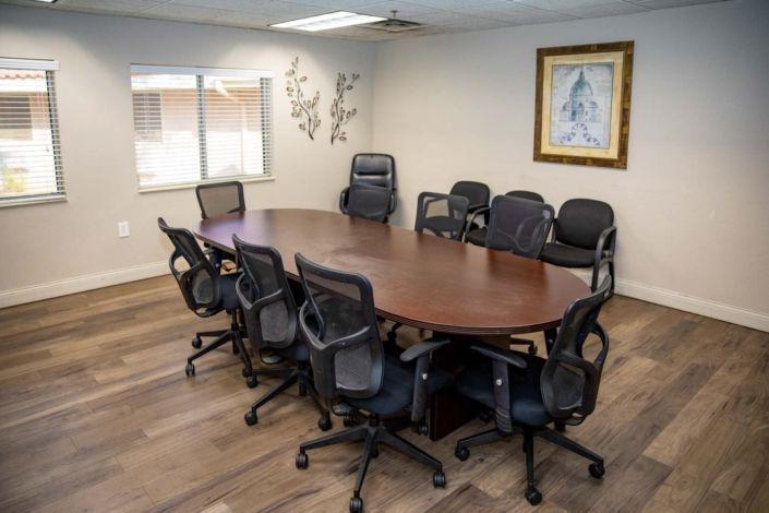 A conference room with a large oval meeting table surrounded by chairs.