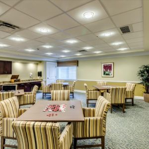 A well-lit communal room with striped chairs and square tables.