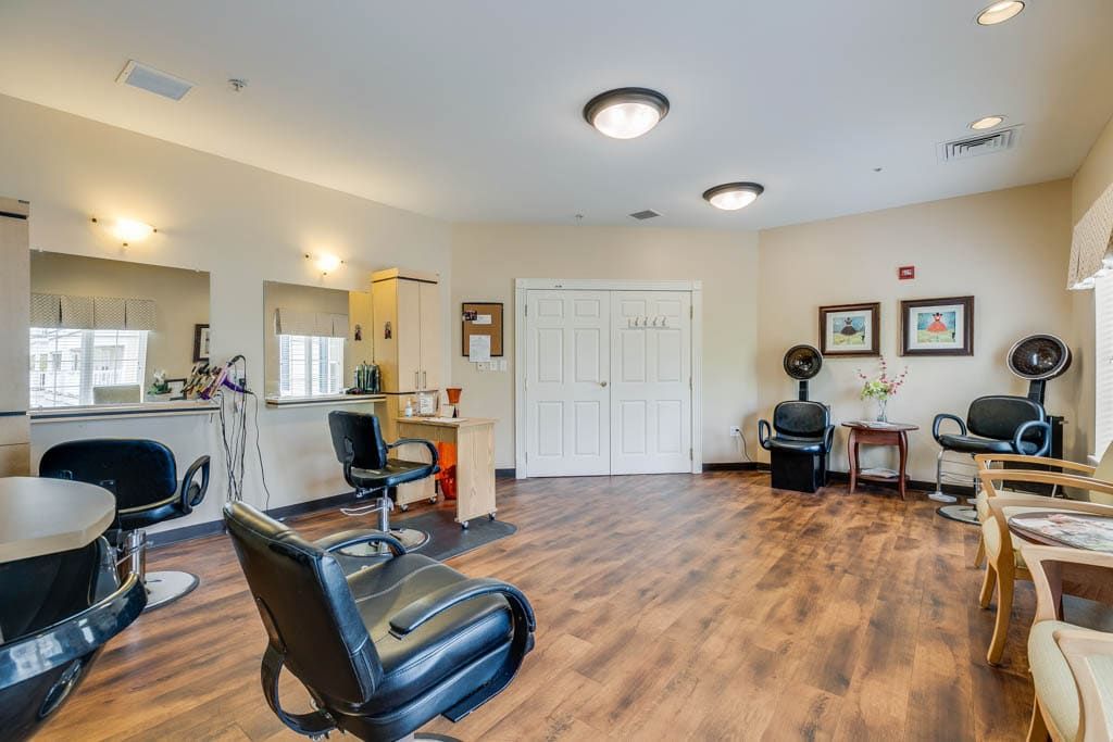 A spacious salon interior featuring modern chairs and wooden flooring.